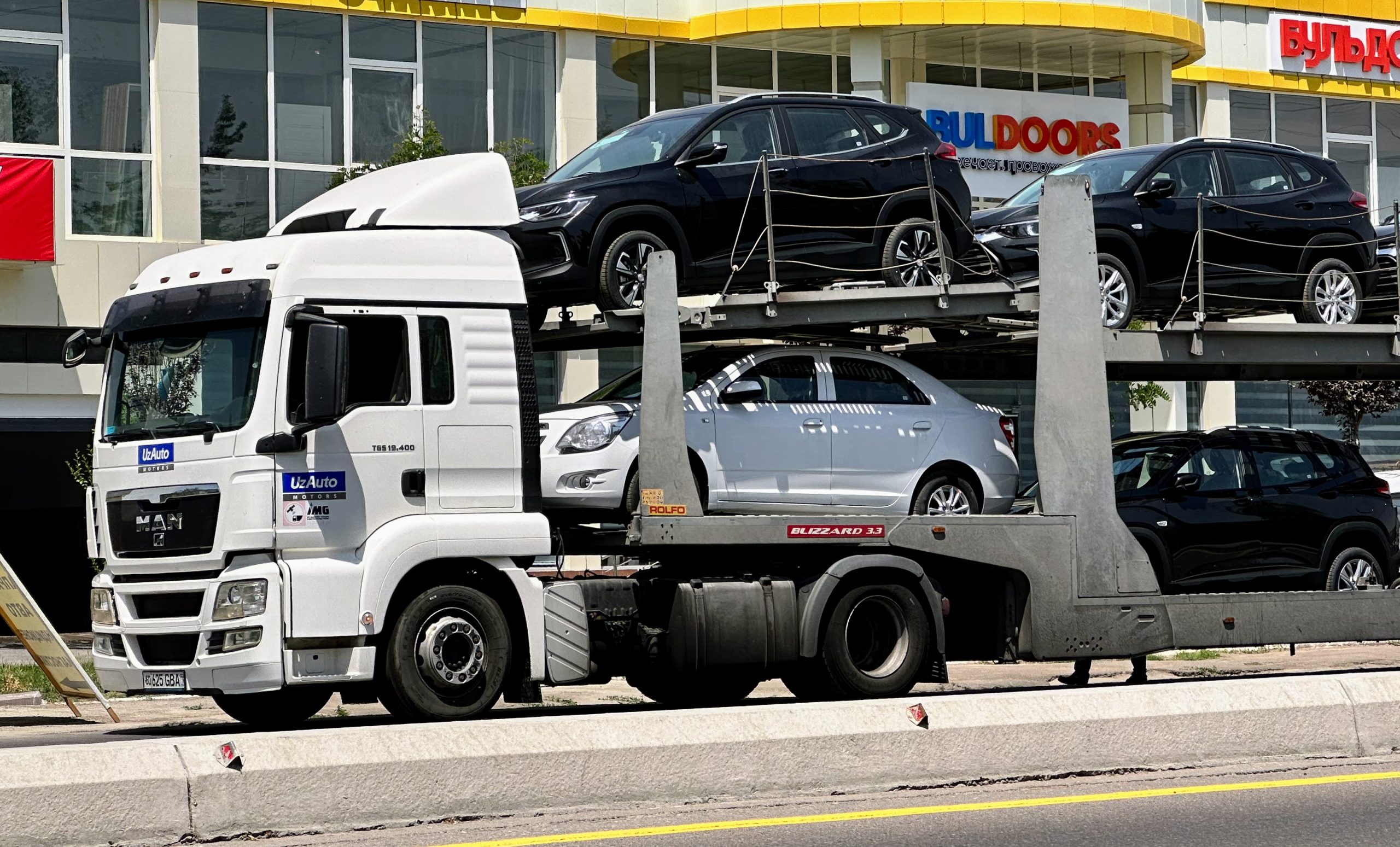 Договора на Gentra и Cobalt будут выдавать через Telegram - 1 Трейлер с автомобилями UzAuto Motors разгружается у автосалона