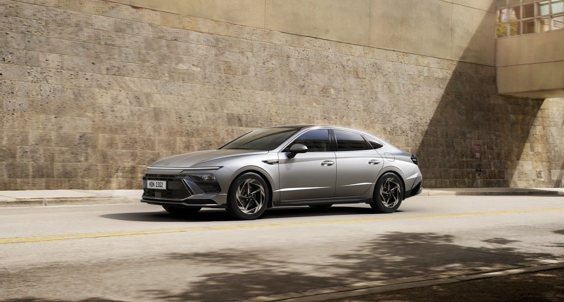 Серая Hyundai Sonata на улице у каменной стены, вид спереди-сбоку