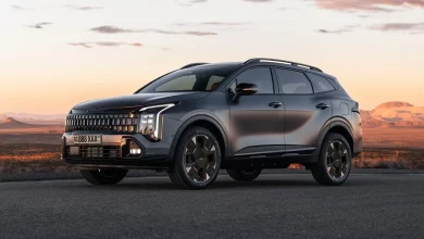 Темно-серый обновленный Kia Sportage спереди сбоку на асфальте в пустыне на закате